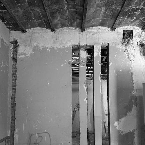 Foto de obra: pared con dos huecos tapiados bajo un techo de vigas de madera