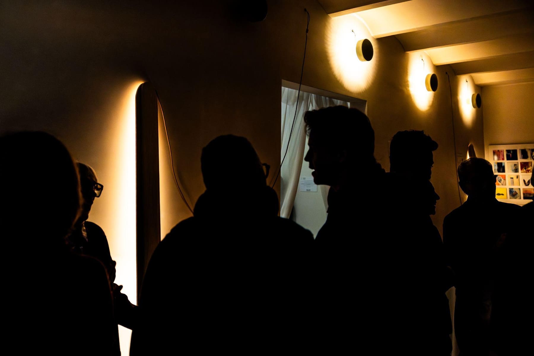 Siluetas de visitantes bajo los apliques de luz